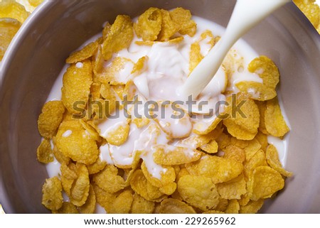 Milk pouring into a bowl of delicious corn flake cereals