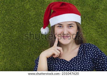 Happy smiling young woman in santa hat  isolated on green background.