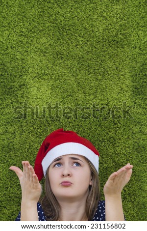 Surprised  young woman with a red santa claus hat looking up.Concept what to choose.Face emotion isolated on green background.