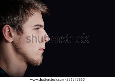 Portrait of young student, man,Head profile portrait side view profile upset,angry,unhappy  isolated black background. Facial expression.