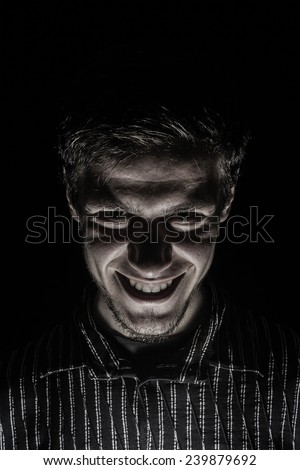Man portrait with evil look isolated on black background.Face expression