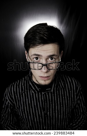 Portrait of a young student,man with eyes wide opened wearing black glasses with amazed facial expression isolated black background.