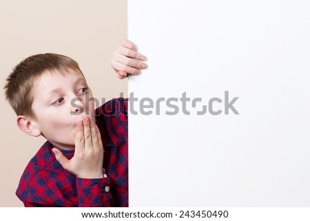 Amazed,Shocked little boy, showing white blank placard, board,poster.Facial expression.