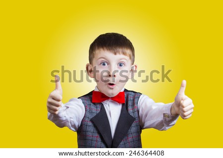 Excited Surprised  little boy with thumb up gesture isolated over yellow background.