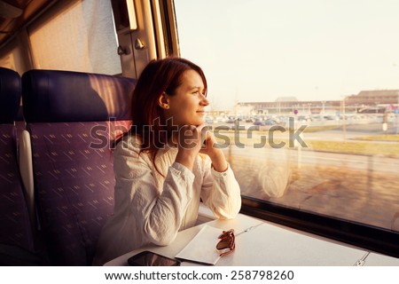 Young woman traveling  looking out the window while sitting in the train.