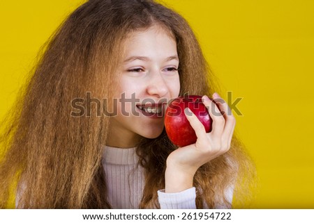 Happy, smiling little girl holding an red apple,  isolated on yellow background.Healthy food,Healthy Thinking,Positive thinking.Idea.
