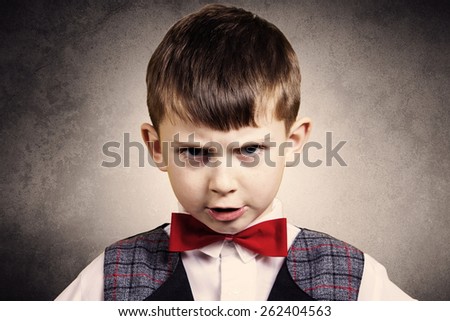 Stubborn,sad,upset  little boy,child  isolated over grey background.Facial expression
