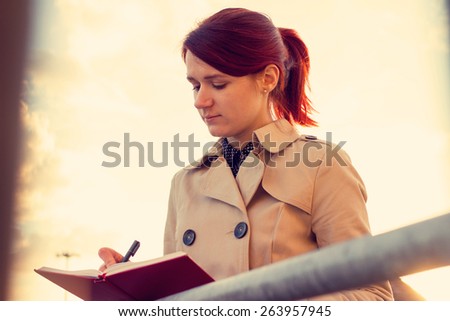 Young businesswoman with a thoughtfully emotion,student professional outdoors holding a red journal.Businesswoman,Life style.