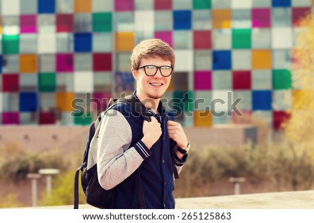 Smiling young man sitting in a city park.Young smiling student  outdoors Life style.Park