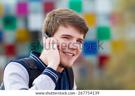 Smiling young man talking on mobile phone in a city .Young smiling student  outdoors talking on cell smart phone.Life style.City