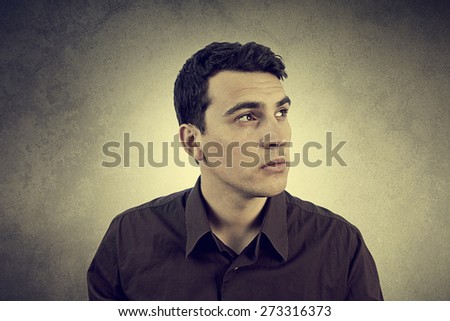 Portrait of a serious man looking up over grey background.Serious young man Student portrait with a thoughtful emotion,expression.