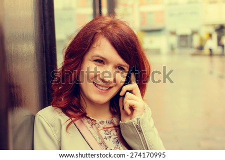 Smiling young girl talking on mobile phone in a city .Young smiling student girl outdoors talking on cell smart phone.Life style.City