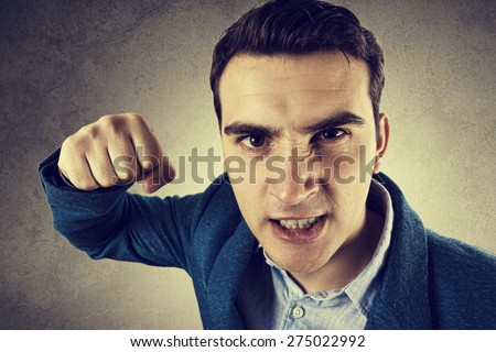 Stressed, aggressive, frustrated portrait of a young student, man,screaming holding his fist up isolated on black background.Facial expression