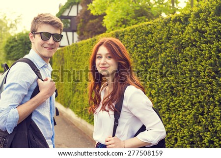 Young student couple  smiling and looking to camera  in a city while taking a walk.Young students outdoors  walking on a city street in a sunny day.Weekend,City,Life style