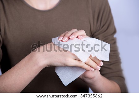 Child Hygiene.Little girl cleaning her hands with a wet baby wipe isolated on a white background.