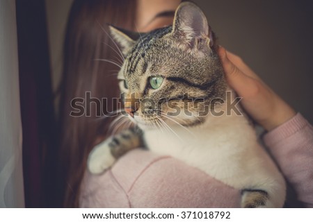 Pets Care.Young woman holding cat home.Cute cat watching and looking on woman\'s arm in home.Friendship.Love