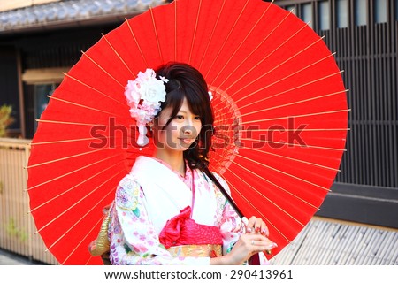 KYOTO,JAPAN - OCTOBER 14: Maiko poses for a photographer with red umbrella on October 14, 2013 in kyoto.