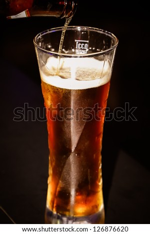 we see how the beer is poured from a bottle into a glass