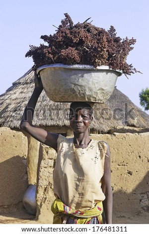 LIGUIDI MANGAM, BURKINA FASO - NOVEMBER 11 : portrait of a woman in her village carrying a load on the head, november 11, 2010