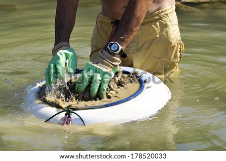 BOUCOIRAN, FRANCE - AUGUST 8: Close up of a washing pan of a golden French researcher named in the river Gardon looking for glitter and gold nuggets, august 8, 2010.