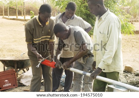 LIGUIDIMALGEM, BURKINA FASO - FEBRUARY 22: installation of a pump in Burkina Faso funded humanitarian associassion. Workers boarding the pumping system at the end of the pipe, February 22, 2007