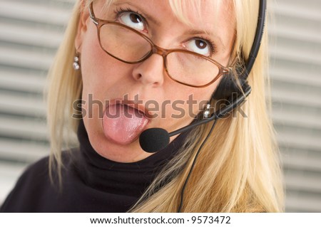 Goofy businesswoman makes a face while she talks on her phone headset.