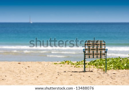 Chair sits on an inviting tropical shore.