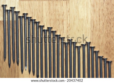 Declining Graph of Nails on a Wood Background.