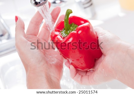 Woman Washing Red Bell Pepper in the Kitchen Sink.