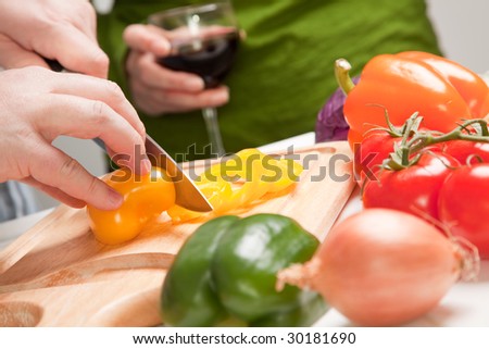 Man Slicing Vegetables on Cutting Board While Woman Enjoys a Glass of Red Wine.