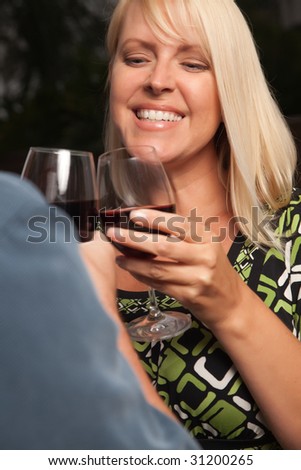 Wine Drinking Blonde Socializing with Man at an Evening Gathering.