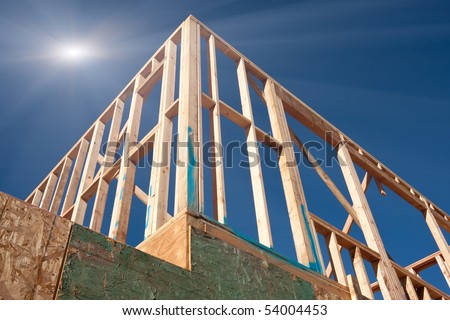 New Construction Framing Abstract with Sunburst Over Clear Blue Sky.