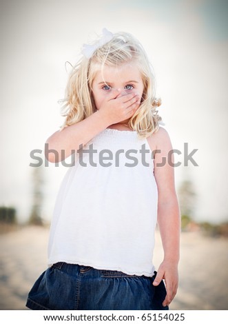 Adorable Blue Eyed Girl Covering Her Mouth Outside.