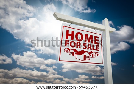 White and Red Home For Sale Real Estate Sign Over Beautiful Clouds and Blue Sky.