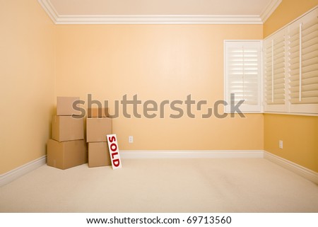 Moving Boxes and Sold Real Estate Sign on Floor in Empty Room with Copy Space on Blank Wall.