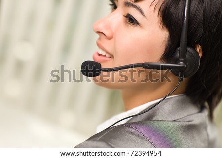 Profile of an Attractive Young Mixed Race Woman Smiles Wearing Headset In An Office Setting.