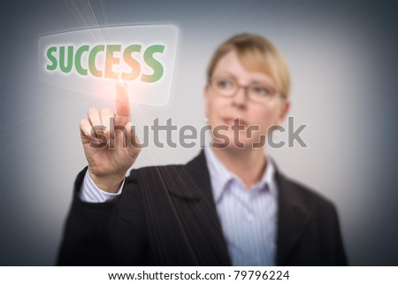 Attractive Blonde Woman Pushing Success Button on an Interactive Touch Screen - Focus is on Her Finger.