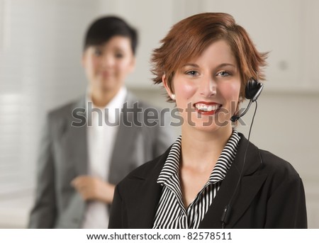 Pretty Red Haired Businesswoman and Colleague with Headset in Office Setting.