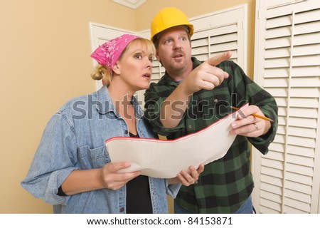Male Contractor in Hard Hat Discussing Plans with Woman in Room.