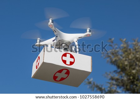 Unmanned Aircraft System (UAS) Quadcopter Drone Carrying First Aid Package In The Air.
