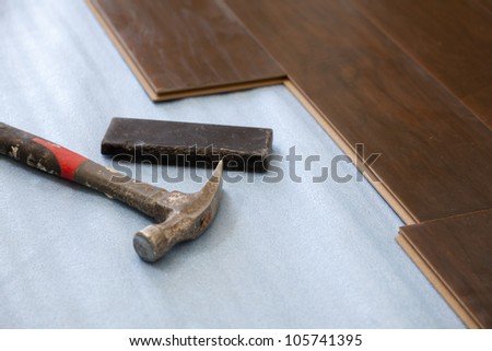Hammer and Block with New Laminate Flooring Abstract.