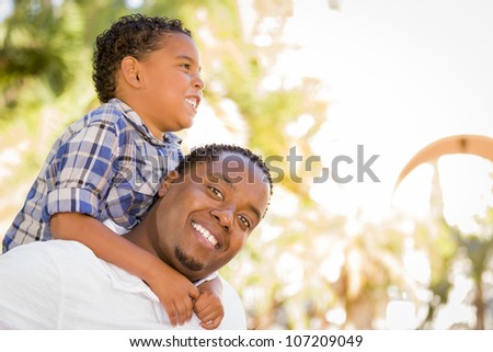 Happy Mixed Race Father and Son Playing Piggyback in the Park.