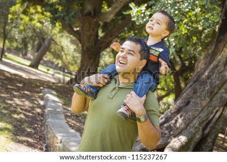 Happy Mixed Race Son Enjoys a Piggy Back Ride in the Park with Dad.