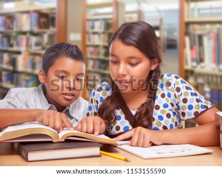 Hispanic Boy and Girl Having Fun Studying Together In The Library.