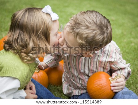 Cute Young Brother and Sister Children Kissing Among the Pumpkins at the Pumpkin Patch.