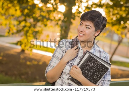 Outdoor Portrait of a Pretty Mixed Race Female Student Holding Books Looking Away.