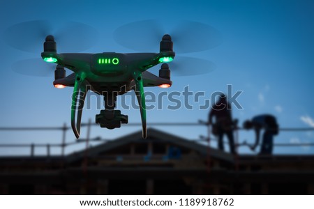 Silhouette of Unmanned Aircraft System (UAV) Quadcopter Drone In The Air at Construction Site.