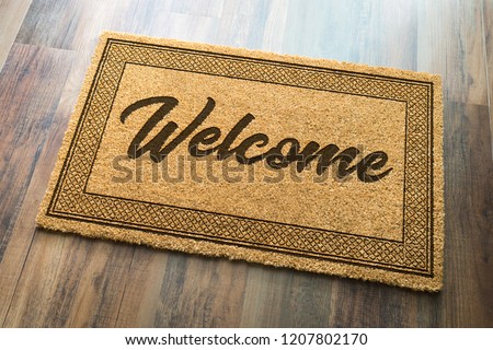 Welcome Mat On A Wood Floor Background.