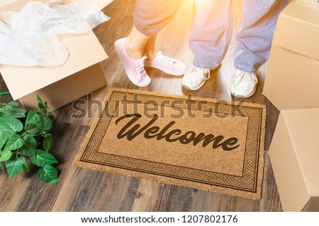 Man and Woman Standing Near Welcome Mat, Moving Boxes and Plant.
