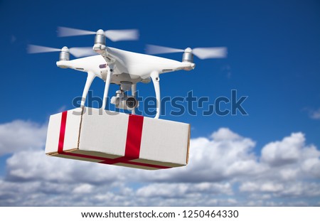 Unmanned Aircraft System (UAV) Quadcopter Drone Delivering Box With Red Ribbon